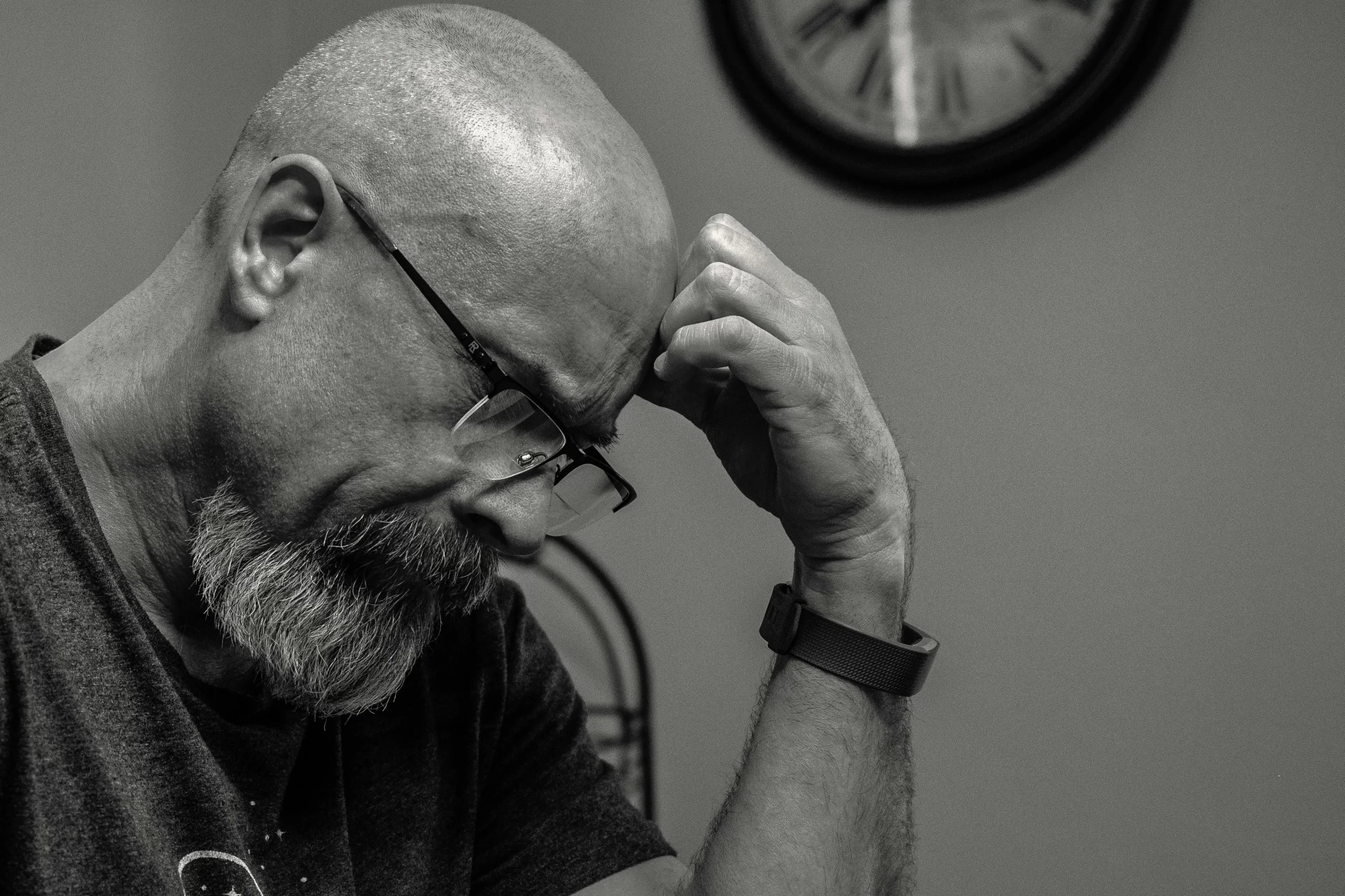 A bald man with glasses looking thoughtful.