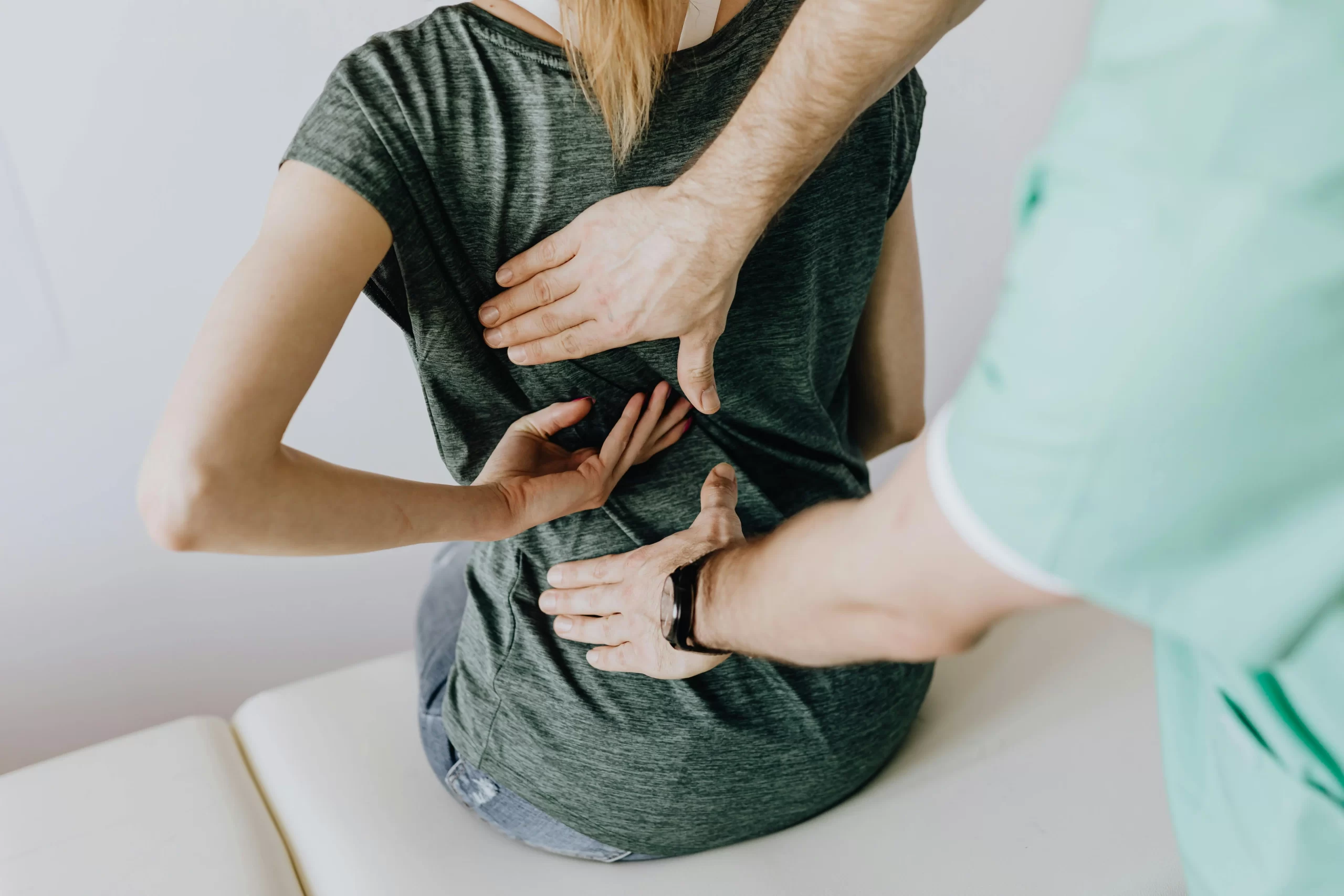 A therapist assessing the back pain of a patient.