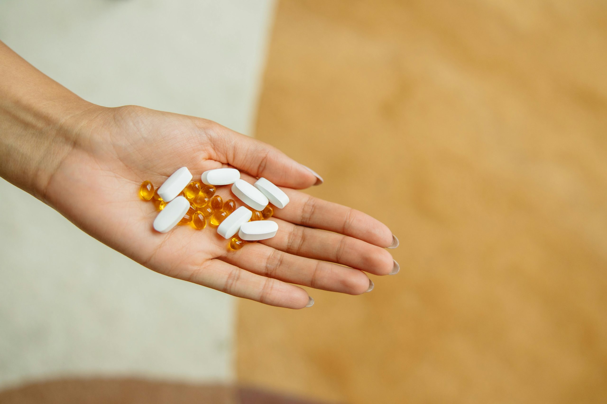 A hand holding many different types of pain relief in pill form.